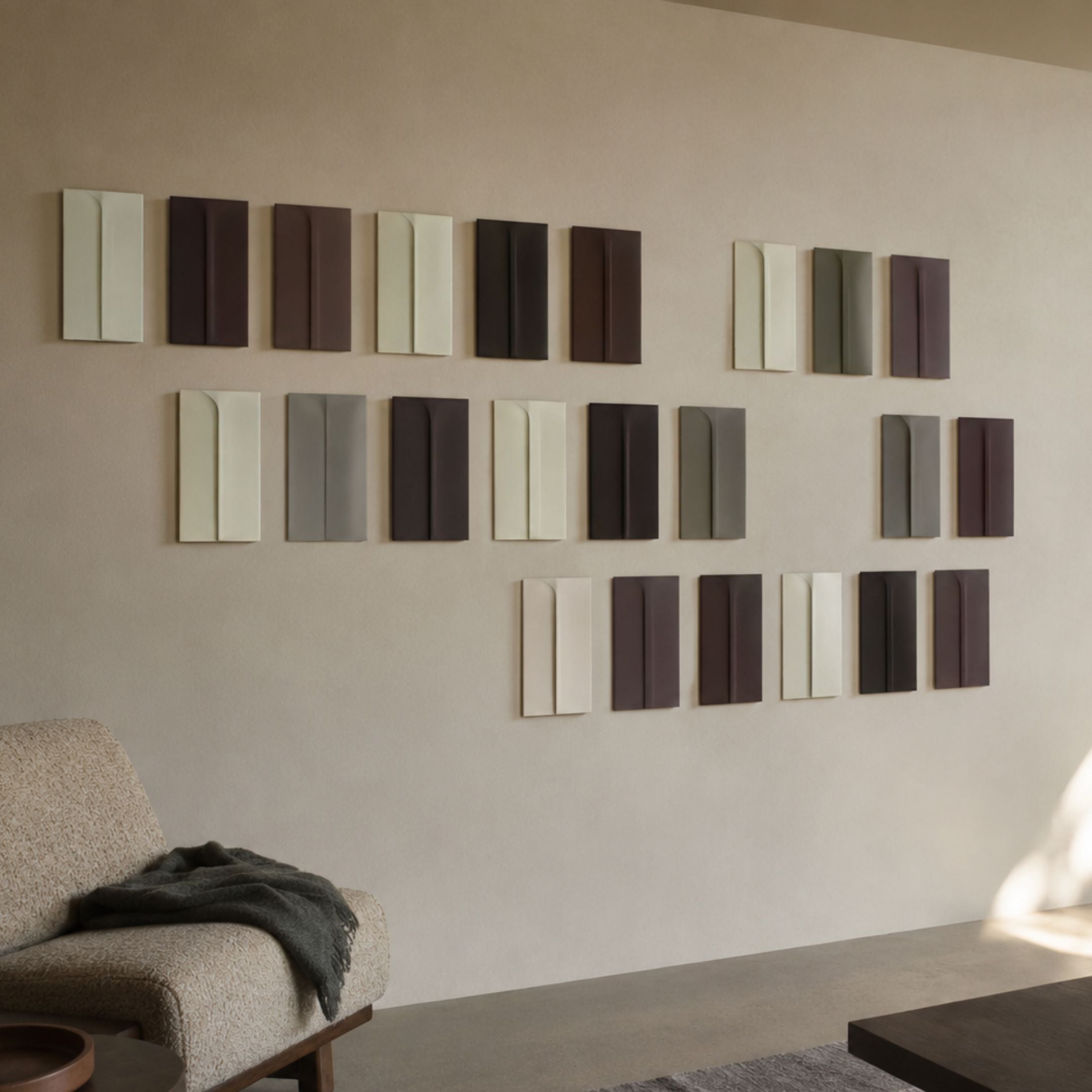Eximia Brown & Grey Tones Multi-Panel Wood Relief 3D Wall Art by Giant Sculptures, staggered cream, brown, grey and green panels above a boucle armchair.