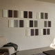 Eximia Brown & Grey Tones Multi-Panel Wood Relief 3D Wall Art by Giant Sculptures, staggered cream, brown, grey and green panels above a boucle armchair.