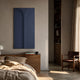 Eximia Blue Minimalist Wood Relief 3D Wall Art by Giant Sculptures mounted above a wooden bedside cabinet in a warm neutral bedroom with linen bedding.