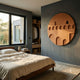 Arcuza Ochre II Wood Carving Sandstone 3D Wall Art by Giant Sculptures, a round ochre relief of stepped arches, mounted on a grey bedroom wall beside a linen bed.