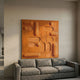 Grida Burnt Orange Wood Carving 3D Wall Art by Giant Sculptures, a square panel of raised rectangles, discs and curves, mounted above a grey sofa.