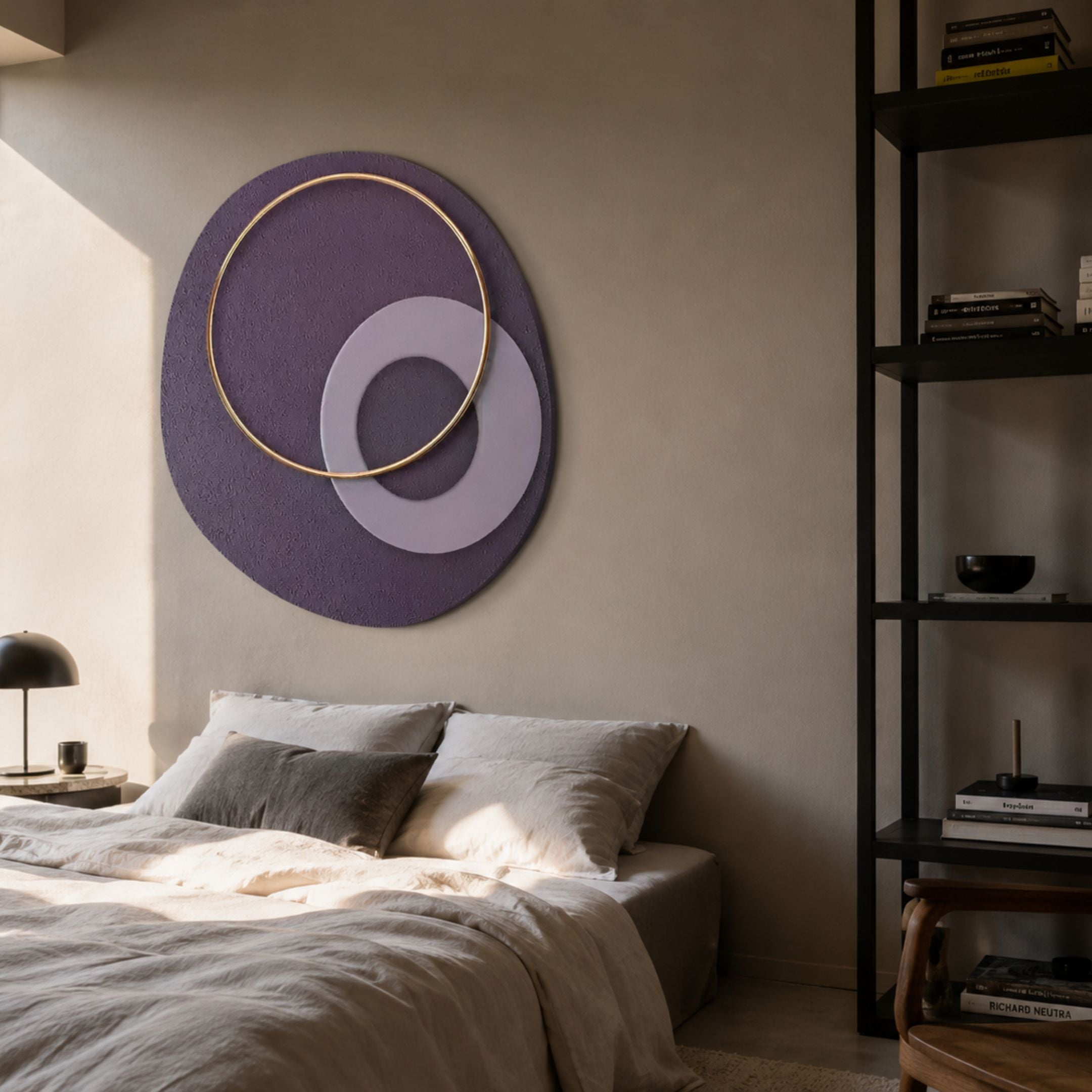 Orbien Plum & Gold Ring Sandstone Mural Wall Art by Giant Sculptures displayed above a linen bed, beside a black shelving unit in a warm-toned bedroom.