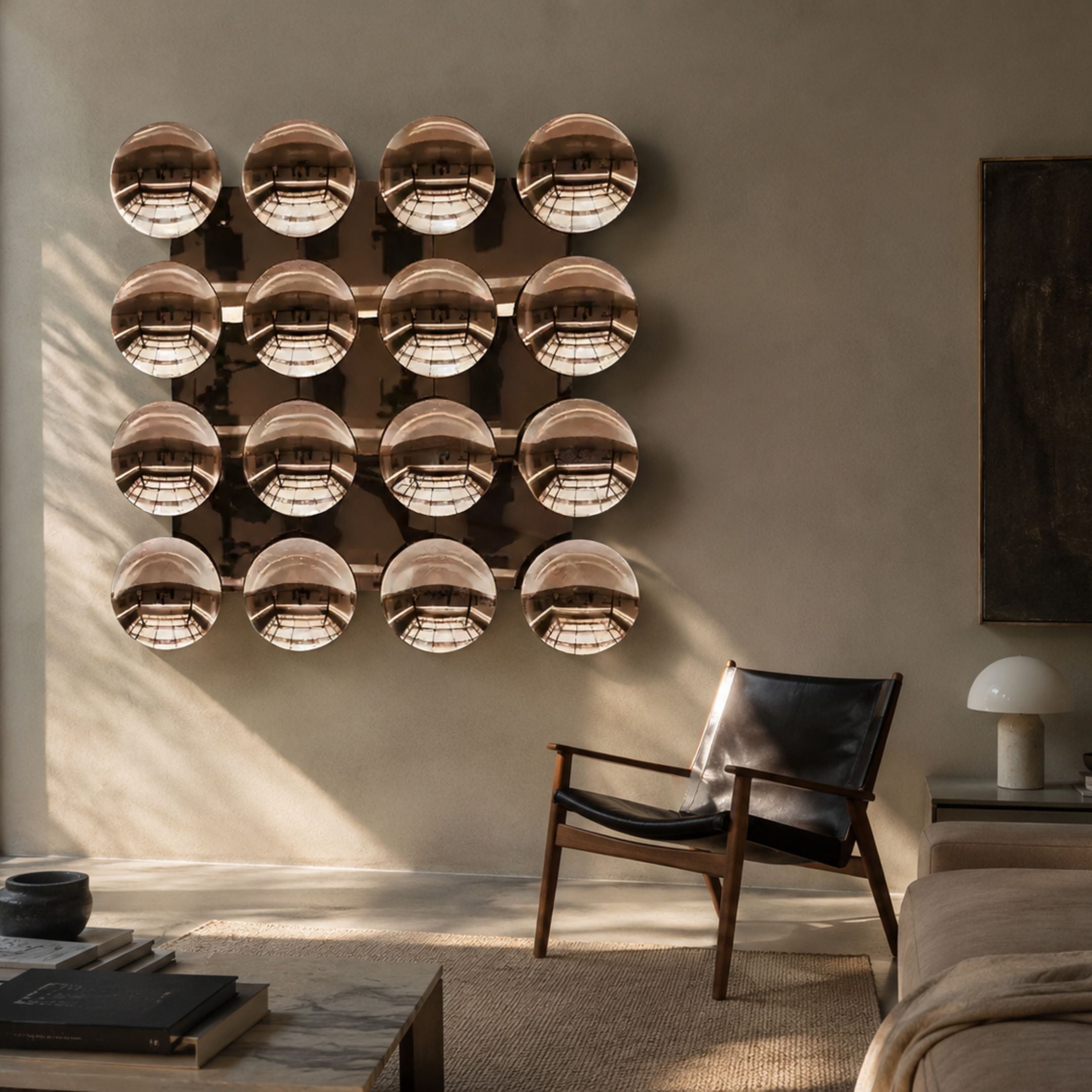 Giant Sculptures Dome Burnished Copper Acrylic 3D Wall Art with sixteen reflective domes in a 4x4 grid, displayed above a black leather chair in a sunlit living room.