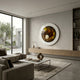 A modern living room with neutral tones, minimalist furniture, floor-to-ceiling window, built-in wooden shelving, a garden view, and the Iriselle Amber Crystal Porcelain Round 3D Wall Art by Giant Sculptures as the focal point.