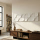 Averra White Linear Wood Relief 3D Wall Art by Giant Sculptures mounted above a walnut media console with vase and headphones in a sunlit living room.