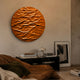 Orenda Ripple Wave Orange Wood Relief 3D Wall Art mounted above a black console table with books and lamp, beside a framed print in a warm living room.