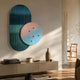 Embera Abstract Circle Pastel Gradient 3D Wall Art by Giant Sculptures, a blue-striped oval overlapped by a pastel pink-to-blue circle with metal spheres, mounted above a sideboard.