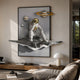 White 3D Galaxy Astronaut Thinker Wall Art by Giant Sculptures, framed sculpted astronaut on rocky ledge with gold-ringed planets, mounted in a modern living room.