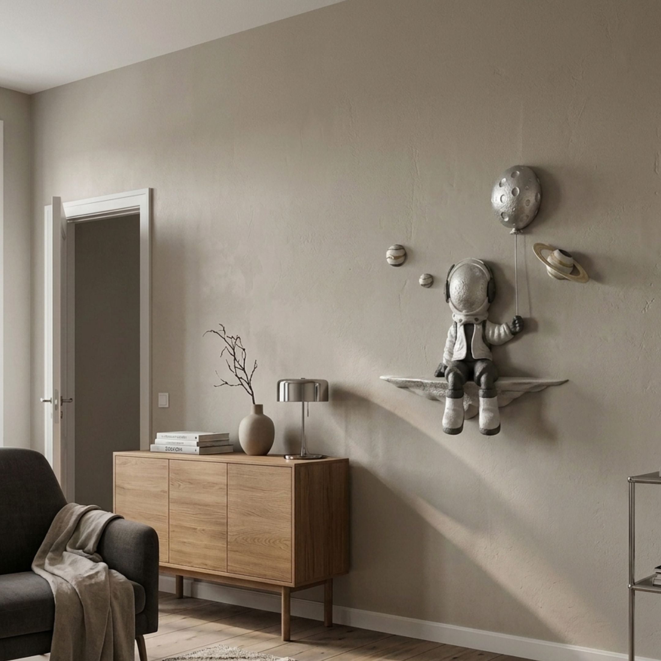 Silver 3D Dreamer Balloon Astronaut Wall Art by Giant Sculptures, mounted in a Nordic living room above a wooden sideboard with lamp and vase.