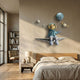 Blue 3D Dreamer Balloon Astronaut Wall Art by Giant Sculptures, with gold visor and teal balloon, mounted above a wooden bed in a neutral-toned bedroom.