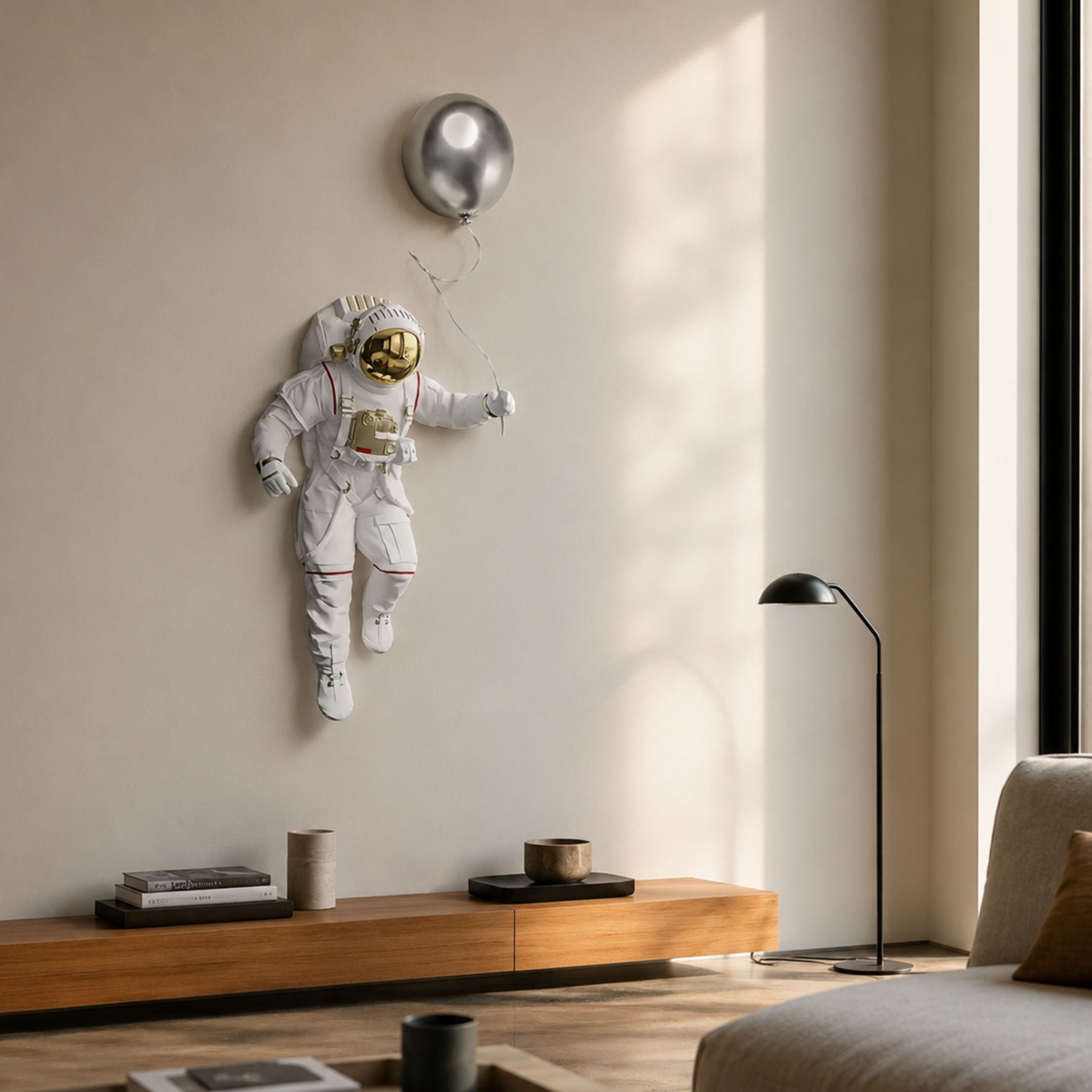 White 3D Cosmic Lift Silver Balloon Astronaut Wall Art by Giant Sculptures mounted in a modern living room above a wooden console with floor lamp.