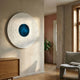 Ventus Azure Depths Wood Carving 3D LED Wall Art by Giant Sculptures, mounted on a beige plaster wall above a wooden sideboard in a sunlit hallway.