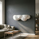 White Geometric Cloud 3D Wall Shelf by Giant Sculptures mounted on a dark grey living room wall above a sofa and wooden coffee table.