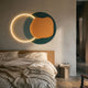 Arcadia Teal Ochre Leather 3D LED Wall Art by Giant Sculptures, illuminated circle paired with teal and ochre forms above an oak bed in a modern bedroom.