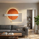 Aeon Sunset Ember Leather 3D LED Wall Art by Giant Sculptures, featuring an orange disc, white bar, and lined panel with backlit glow, above a grey sofa in a living room.