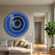 Reflex Sapphire Mirror 3D LED Wall Art by Giant Sculptures mounted above a beige sofa in a sunlit living room, with concentric blue rings creating a tunnel effect.