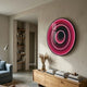 Reflex Crimson Mirror 3D LED Wall Art by Giant Sculptures, a round pink and red illuminated concentric ring piece mounted above a wooden console in a living room.
