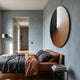 Orbit Copper Hand-Painted Canvas 3D LED Wall Art by Giant Sculptures mounted above a bed with grey and copper linens in a modern blue-grey bedroom.