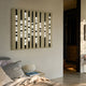 Strata Slate LED Wall Art by Giant Sculptures mounted above a side table in a neutral living room, its vertical black rods glowing with white striped segments.