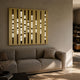 Strata Gold LED Wall Art by Giant Sculptures mounted above a beige sofa, showing nine vertical black bands with warm glowing LED segments on a gold panel.