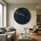 Orbura Dark Blue Circular 3D Wood Relief Wall Art mounted above a linen sofa in a modern living room with a leather armchair and bookshelf.
