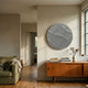 Orbura Grey Circular 3D Wood Relief Wall Art by Giant Sculptures mounted on a beige wall above a teak sideboard in a modern living room with an olive sofa.