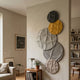 Orbura 5-Set Circular Grey & Yellow 3D Wood Relief Wall Art by Giant Sculptures displayed in a beige living room with armchair, side table, and bookshelf.