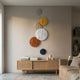 Orbura 6-Set Circular Earth-Tone 3D Wood Relief Wall Art by Giant Sculptures in grey, mustard, beige, white, rust, and navy above a rattan sideboard.