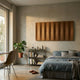 Vireus Brown Rectangular 3D Wood Relief Wall Panel by Giant Sculptures, mounted above a shelf in a neutral bedroom with linen bedding, monstera plant, and chair.
