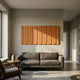 Vireus Bronze 3D Wood Relief Wall Panel by Giant Sculptures mounted above a grey sofa in a sunlit living room with a wooden side table and vase.