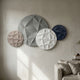 Orbita 4-Set Circular Monochrome 3D Wood Relief Wall Art by Giant Sculptures in grey, white, beige and navy, mounted above a linen sofa on a cream wall.