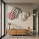 Orbita 4-Set Circular Blush & Ivory 3D Wood Relief Wall Art by Giant Sculptures displayed above a wooden sideboard with pampas grass and chair in a sunlit hallway.