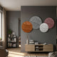 Orbita 4-Set Circular Rust & Blush 3D Wood Relief Wall Art by Giant Sculptures displayed on a dark grey living room wall above an oak console with books.