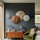 Giant Sculptures Orbita 5-Set Circular Terra & Ivory 3D Wood Relief Wall Art clustered on a dark grey wall above a teak sideboard and olive armchair.