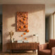 Fluxion Orange 3D Wood Relief Wall Art with glossy metal spheres mounted above a walnut sideboard with vases, books, and lamp in a warm-toned living room.