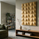 Ondula Textured Gold Wood Relief 3D Wall Art by Giant Sculptures mounted above a wooden console in a modern living room with a green sofa and bookshelf.