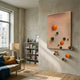 Sphera Amber 3D Wood Relief Wall Art by Giant Sculptures, mounted in a sunlit living room with bookshelf, sofa, and lamp, featuring gold and orange spheres.