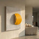 Solvara Yellow & White Wood Relief 3D Wall Art by Giant Sculptures mounted in a neutral living room beside a linen sofa, featuring a yellow crescent on carved waves.