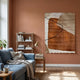 Terracurve II Hand-Painted Sandstone Wood Relief 3D Wall Art by Giant Sculptures displayed on a terracotta living room wall above a blue sofa and bookshelf.