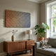 Spectrum Weave Horizontal Earthy Ombre Wood Relief 3D Wall Art by Giant Sculptures mounted above a walnut sideboard in a living room with monstera plant.
