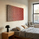Spectrum Weave Horizontal Rose Blush Wood Relief 3D Wall Art mounted above a linen-dressed bed with oak nightstand and black dome lamp in a sunlit bedroom.