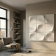 Curvatura White Grid 3D Wood Relief Wall Art by Giant Sculptures, a nine-tile carved composition mounted in a minimalist living room with a grey armchair and bookshelf.