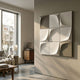 Curvatura 3D Wood Relief Wall Art by Giant Sculptures, nine sculpted tiles in white and grey tones, mounted on a pale wall in a sunlit modern living room.