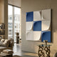 Curvatura White & Blue Grid 3D Wood Relief Wall Art by Giant Sculptures mounted in a modern living room beside a glass side table and large window.