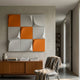 Curvatura White & Orange Grid 3D Wood Relief Wall Art by Giant Sculptures displayed above a wooden sideboard with books and a vase in a minimalist room.