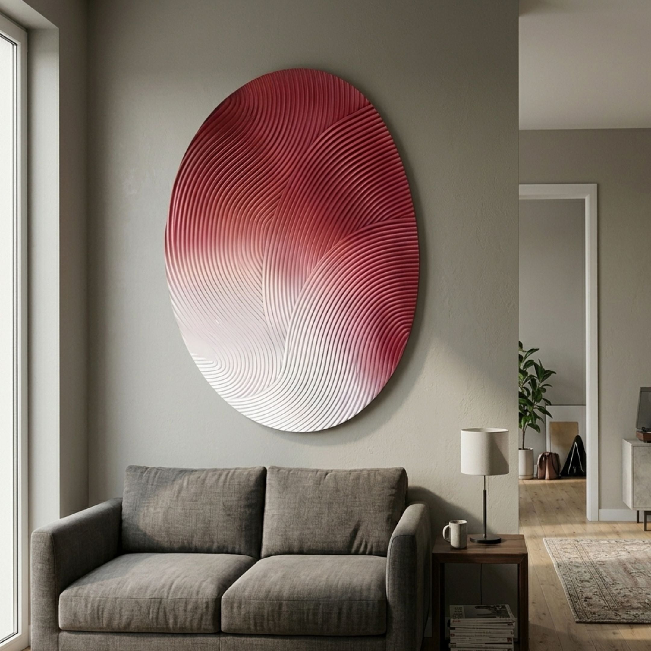 Fluctus Red Textured Sandstone Wood Relief 3D Wall Art by Giant Sculptures, oval panel with red-to-white wave ripples, displayed above a grey sofa in a living room.