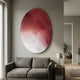 Fluctus Red Textured Sandstone Wood Relief 3D Wall Art by Giant Sculptures, oval panel with red-to-white wave ripples, displayed above a grey sofa in a living room.