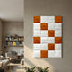 Vellura White & Orange Textured Wood Relief 3D Wall Art by Giant Sculptures mounted on a beige wall in a modern living room with bookshelf and armchair.