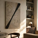 Artura Ivory Hand-Painted 3D Relief Wall Art by Giant Sculptures with concentric ridges and a black diagonal strip, displayed in a sunlit living room beside a bookshelf.