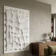 Novara White II Hand-Painted Wood Relief 3D Wall Art by Giant Sculptures displayed on a grey wall above a walnut sideboard with books and a lamp.